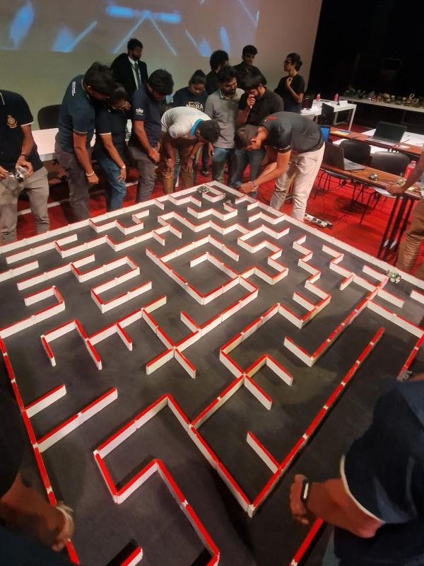 Robofest competition maze with a grid of wall-bounded passages and participants around the arena